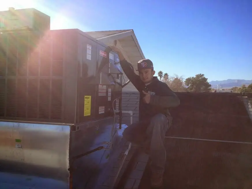 HVAC technician performing Boiler Repair on a rooftop unit in Victorville