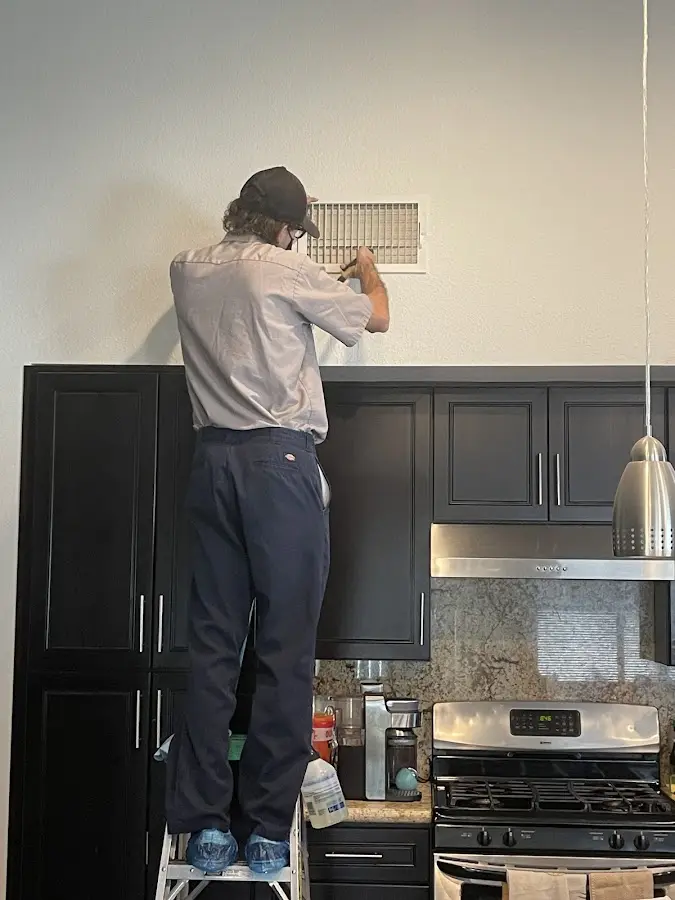 Technician inspecting an air vent during HVAC service in Victorville